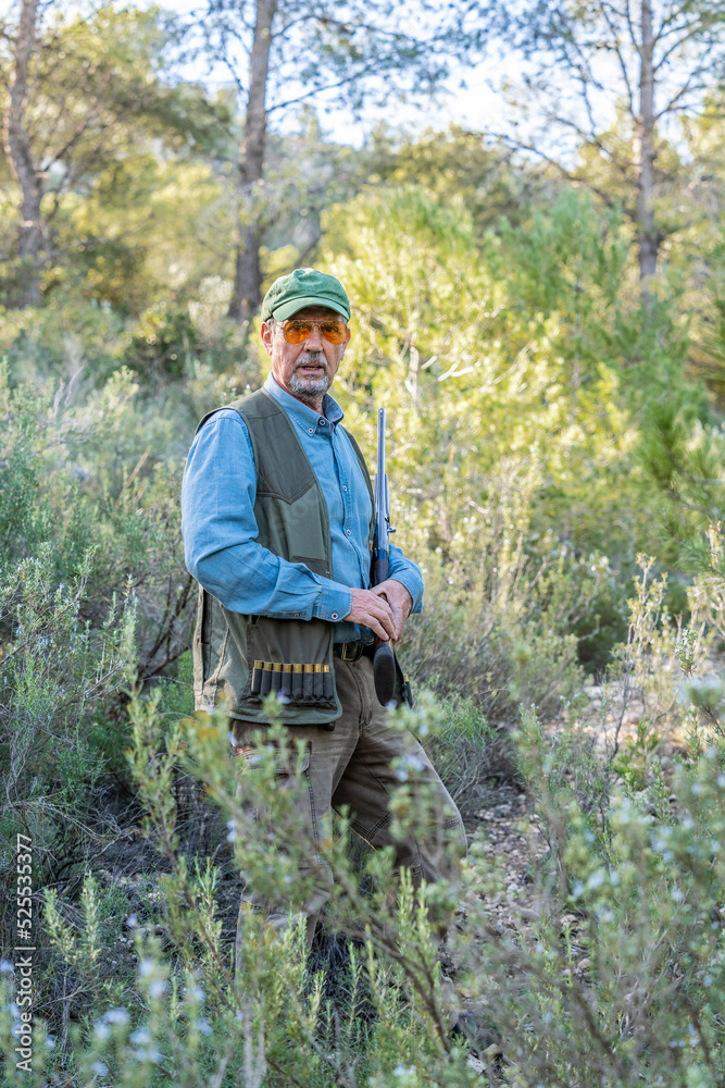 Aged man in camouflage clothing hunting in nature Aged man in camouflage clothing hunting in nature