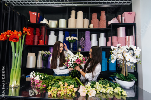 Two young women take orders and make up a beautiful festive bouquet in a cozy flower shop. Floristry and making bouquets in a flower shop. Small business.