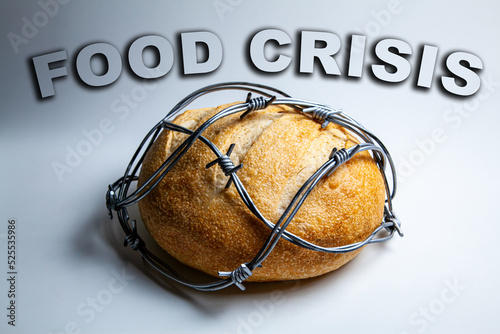 A loaf of round wheat bread wrapped with barbed wire. The concept of food crisis, food shortage