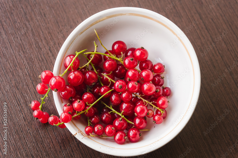 Sprigs of red currant in a white bowl closeup top view. Sweet red currant spilling out from the bowl. Currant organic berries harvest - healthy eating and food concept Sprigs of red currant in a white bowl closeup top view. Sweet red currant spilling out from the bowl. Currant organic berries harvest - healthy eating and food concept