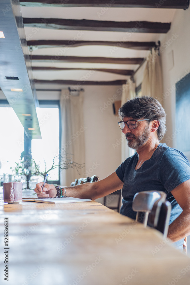 Serious adult man taking notes in notepad at cafe Serious adult man taking notes in notepad at cafe