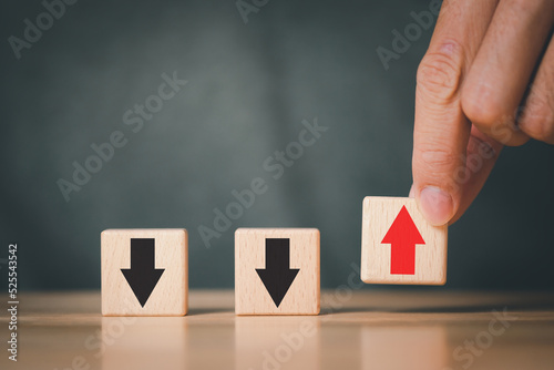 Hand putting up red arrow on wooden cube block on black arrow which opposite direction. Contrast different thinking and disruption concept.