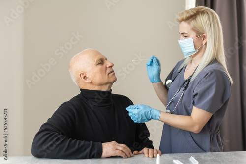 Nurse performing a coronavirus pcr test on an elderly man in his home