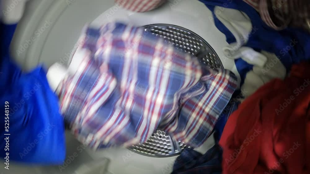 Slow motion video of clothes tumbling inside laundry dryer.