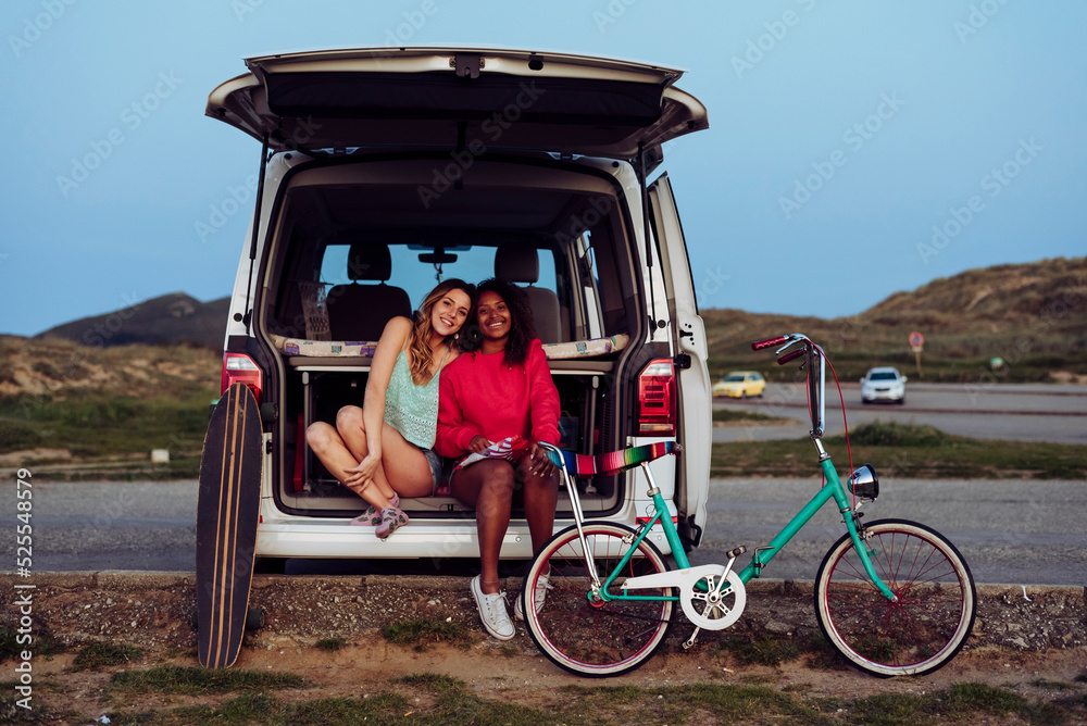 Cheerful women sitting on trunk of van Cheerful women sitting on trunk of van