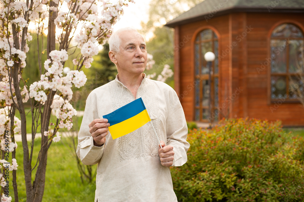 Senior man with Ukrainian flag. Elderly man in national clothes with the flag of Ukraine. The concept of nation, independence, protest, peace, stop war in Ukraine. The independence day of Ukraine Senior man with Ukrainian flag. Elderly man in national clothes with the flag of Ukraine. The concept of nation, independence, protest, peace, stop war in Ukraine. The independence day of Ukraine