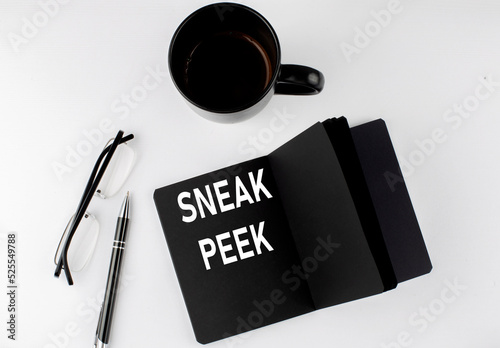 SNEAK PEEK written text in small black notebook with coffee , pen and glasess on white background. Black-white style
