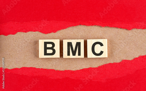 BMC word on wooden cubes on red torn paper