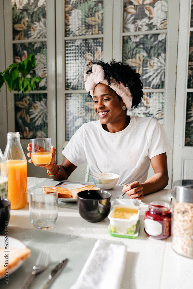 Happy ethnic woman enjoying juice during breakfast Happy ethnic woman enjoying juice during breakfast