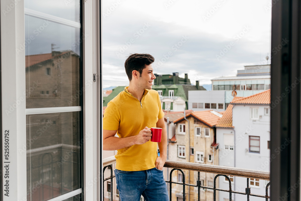 Attractive caucasian man with a coffee cup on the balcony