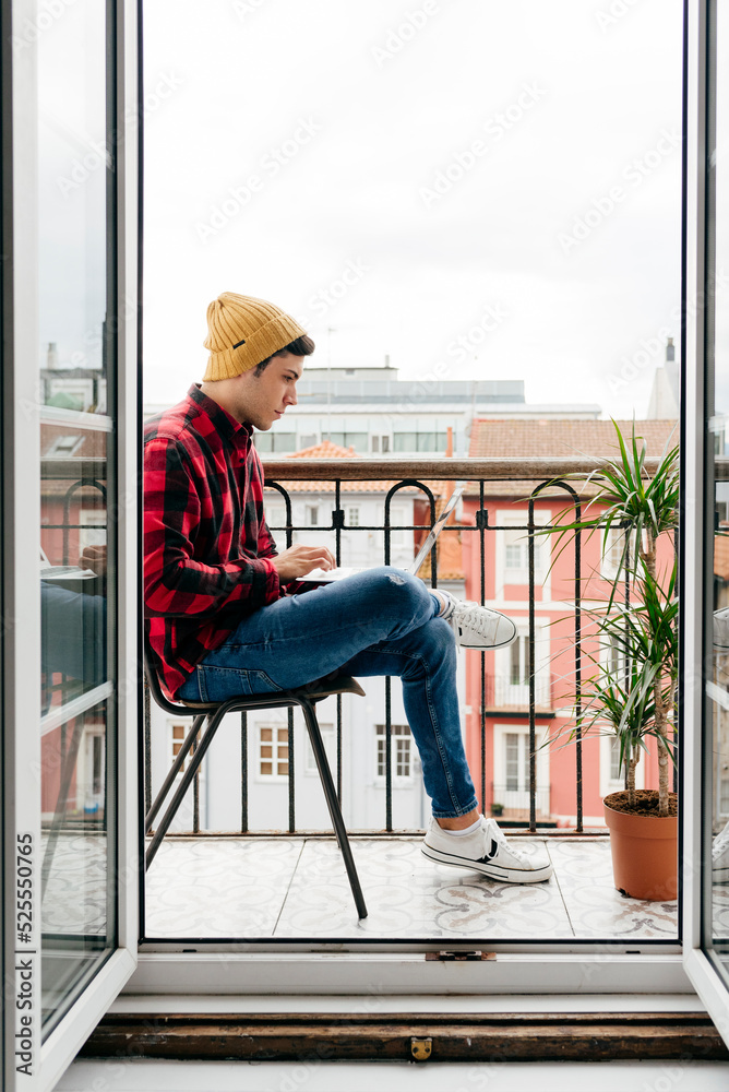 Man sitting on the balcony using the laptop at home Man sitting on the balcony using the laptop at home