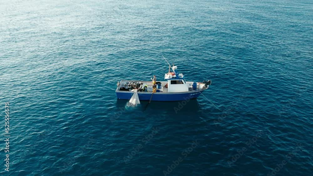 Effective team work of fisherman crew pulling out trawl with sardines from deep blue sea on their vessel. Aerial shot, early morning, alone in ocean Effective team work of fisherman crew pulling out trawl with sardines from deep blue sea on their vessel. Aerial shot, early morning, alone in ocean
