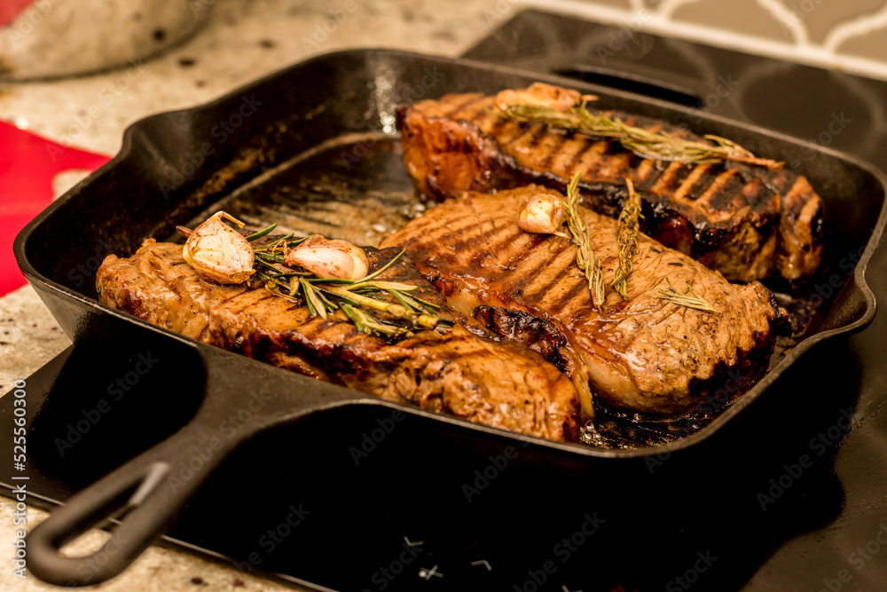 Grilling new york strip sirloin beef steaks with rosemary and garlic on