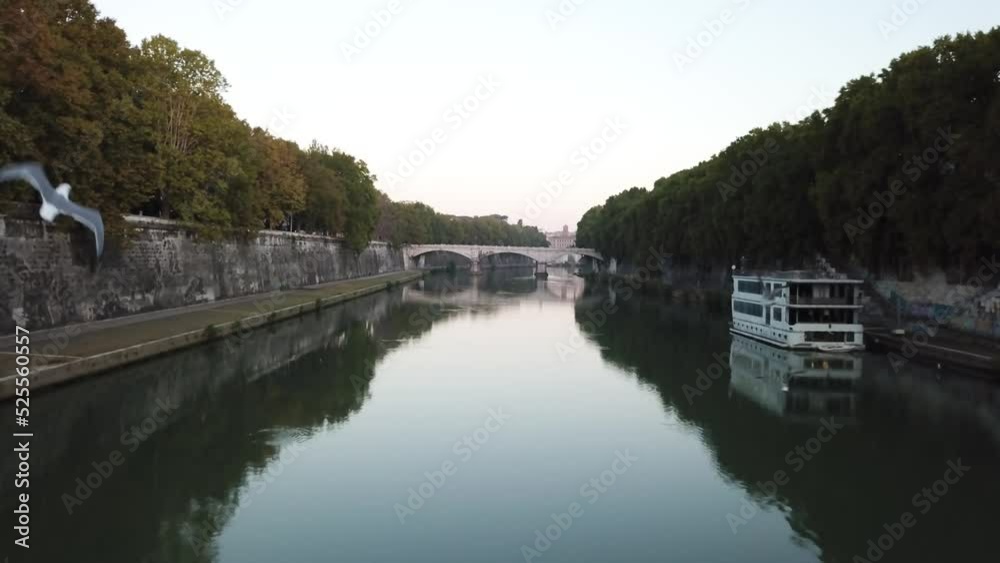 Drone flying above the river that runs through the city of Rome, Italy, with several houses in the backdrop Drone flying above the river that runs through the city of Rome, Italy, with several houses in the backdrop