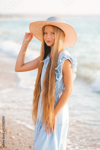 Wallpaper Mural Beautiful smiling blonde teenager girl 12-14 year old with long hair wear straw hat and stylish elegant dress stand over sea coast outdoor. Summer season. Childhood. Torontodigital.ca
