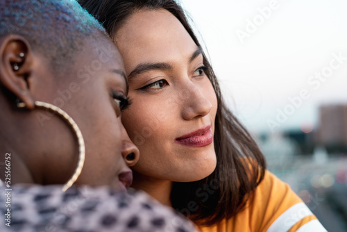 Multiracial lesbian couple sitting close together outdoors
