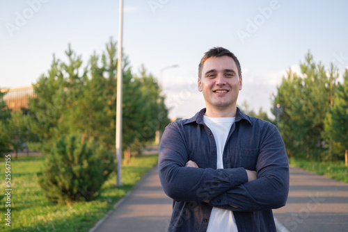 a businessman walking in a city park with a cup of coffee. a happy man walking down the street in the daytime.