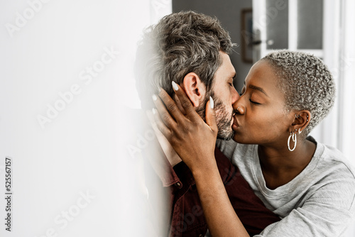 Young multiethnic lovers during tender kiss at table photo