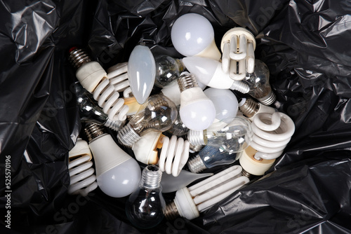The black trash bag contains a lot of old energy-saving fluorescent lamps, used incandescent lamps for recycling.View from above. Hazardous and toxic waste