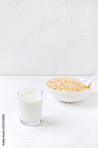 bowl of granola with a spoon and a glass of oat milk. white wooden background. top view. copy space.