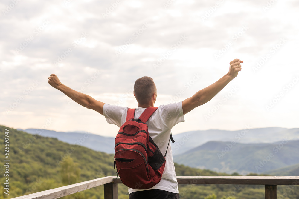 Guy tourist with a backpack stands in the mountains on a meadow with a backpack on his back Guy tourist with a backpack stands in the mountains on a meadow with a backpack on his back