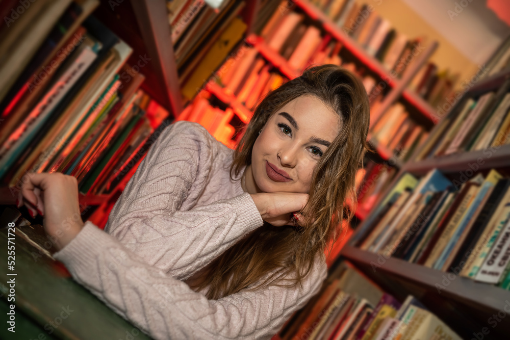 beautiful cute happy lady enthusiastically reads one book after another in a modern library. beautiful cute happy lady enthusiastically reads one book after another in a modern library.