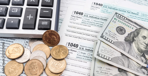 Blank personal income tax return with dollar bills and calculator and pen on calendar