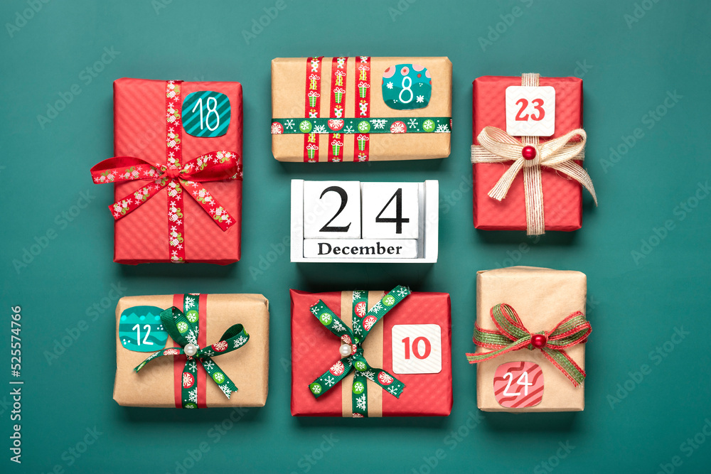 Fototapeta premium Handmade wrapped red, green gift boxes decorated with ribbons, snowflakes and numbers, Christmas decorations and decor on green table Xmas advent calendar concept Top view Flat lay Holiday card