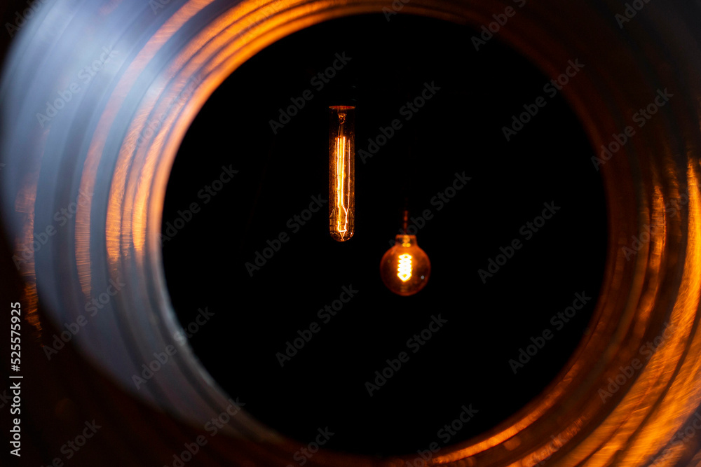 glowing bulbs with edison filament visible from the ventilation duct through the grate, the front and back background is blurred with bokeh effect glowing bulbs with edison filament visible from the ventilation duct through the grate, the front and back background is blurred with bokeh effect