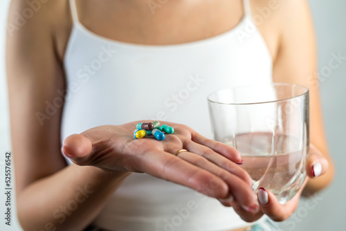 cropped photo of a beautiful young girl with a diet pill in one hand and a glass in the other. © RomanR