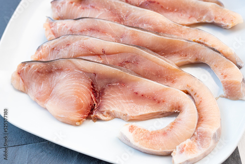Close-up of various slices of raw swordfish, in a white plate, on a slate table..Tasty food from Italian cuisine and from the Mediterranean sea. Concept for a tasty and healthy meal.