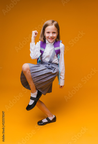 Back to school. A schoolgirl holds books in her hands. a little girl on an isolated yellow studio background. Run and jump, jumping baby. back to school