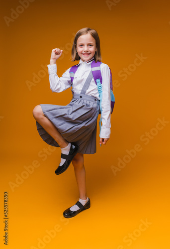 Back to school. A schoolgirl holds books in her hands. a little girl on an isolated yellow studio background. Run and jump, jumping baby. back to school