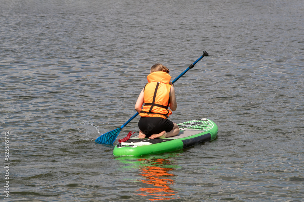 Obraz premium SUP surfboard. A young woman floats on a beautiful calm lake. The concept of summer holidays, travel, vacation, active and healthy life in harmony with nature.