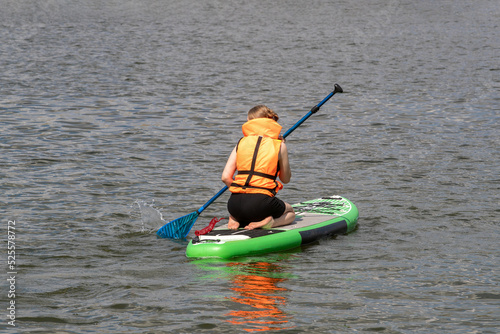 SUP surfboard. A young woman floats on a beautiful calm lake. The concept of summer holidays, travel, vacation, active and healthy life in harmony with nature.