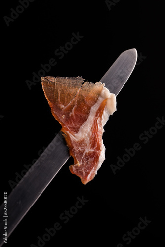 Delicious thin ham slice on black background photo