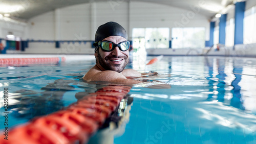 Smiling swimmer leaning on lane divider in pool photo