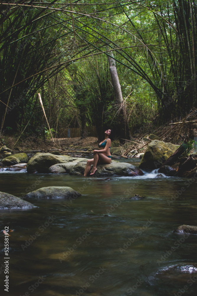 Girl on vacation in a spa. Girl bathing in a river. Woman with hat. River with stones and bamboo Girl on vacation in a spa. Girl bathing in a river. Woman with hat. River with stones and bamboo