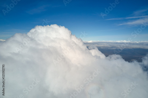 Aerial view from airplane window at high altitude of earth covered with white puffy cumulus clouds © bilanol