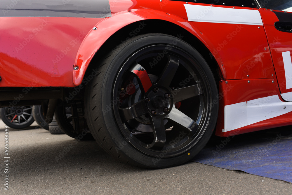 Tires of race car for driving. Drag and drift car with lower-profile tire. Racing low profile tyre with brake disc. Alloy wheel with calipers and racing brakes of the sport cars. Tyres background..