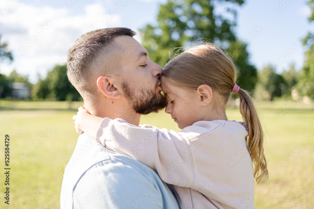 stylish bearded father with his little daughter in his arms on a walk in the summer park hugging and kissing stylish bearded father with his little daughter in his arms on a walk in the summer park hugging and kissing