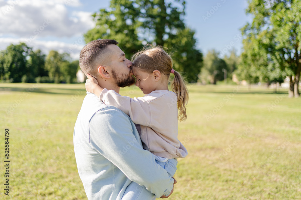 stylish bearded father with his little daughter in his arms on a walk in the summer park hugging and kissing stylish bearded father with his little daughter in his arms on a walk in the summer park hugging and kissing