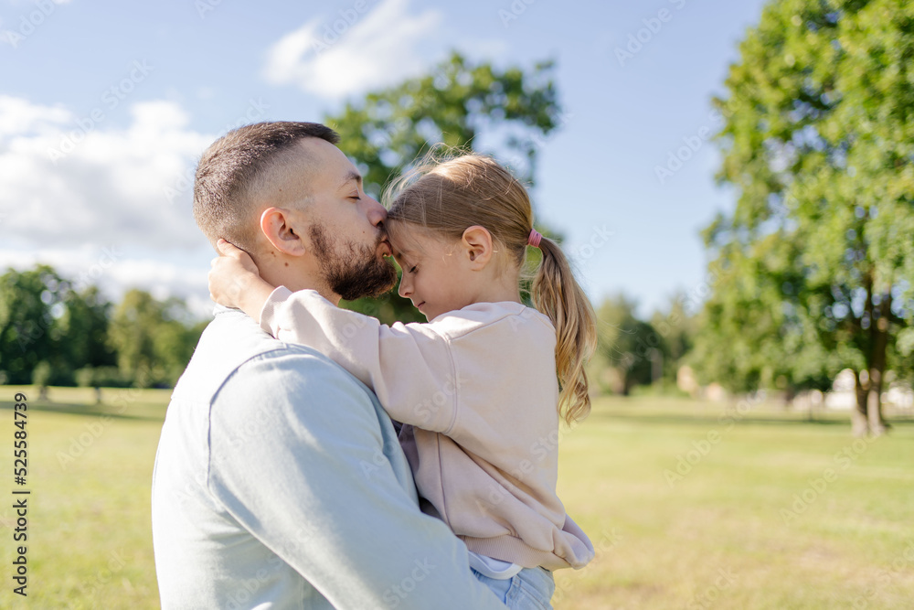 stylish bearded father with his little daughter in his arms on a walk in the summer park hugging and kissing stylish bearded father with his little daughter in his arms on a walk in the summer park hugging and kissing