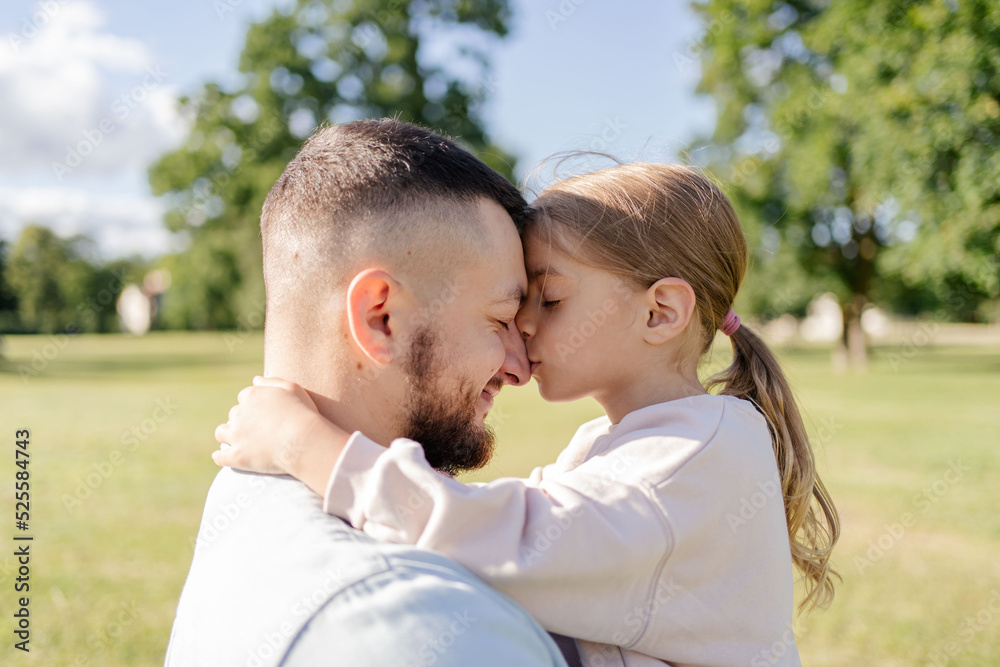 Daughter hugging and kissing her father in the park, father and daughter outdoors smiling face to face Daughter hugging and kissing her father in the park, father and daughter outdoors smiling face to face