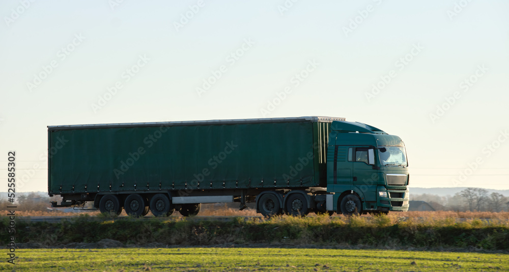Semi-truck with cargo trailer driving on highway hauling goods in evening. Delivery transportation and logistics concept Semi-truck with cargo trailer driving on highway hauling goods in evening. Delivery transportation and logistics concept