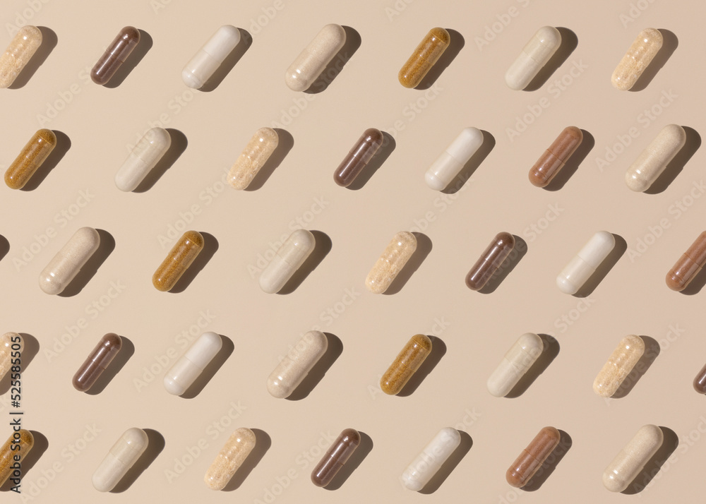 Creative pattern with capsules on light beige top view, hard shadows. Taking supplements Creative pattern with capsules on light beige top view, hard shadows. Taking supplements