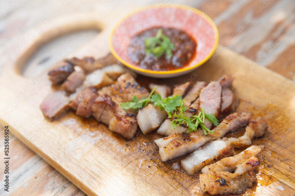Grilled pork neck marinated in the hot sauce from the grill. Tasty slice grilled pork on wooden board,thai food