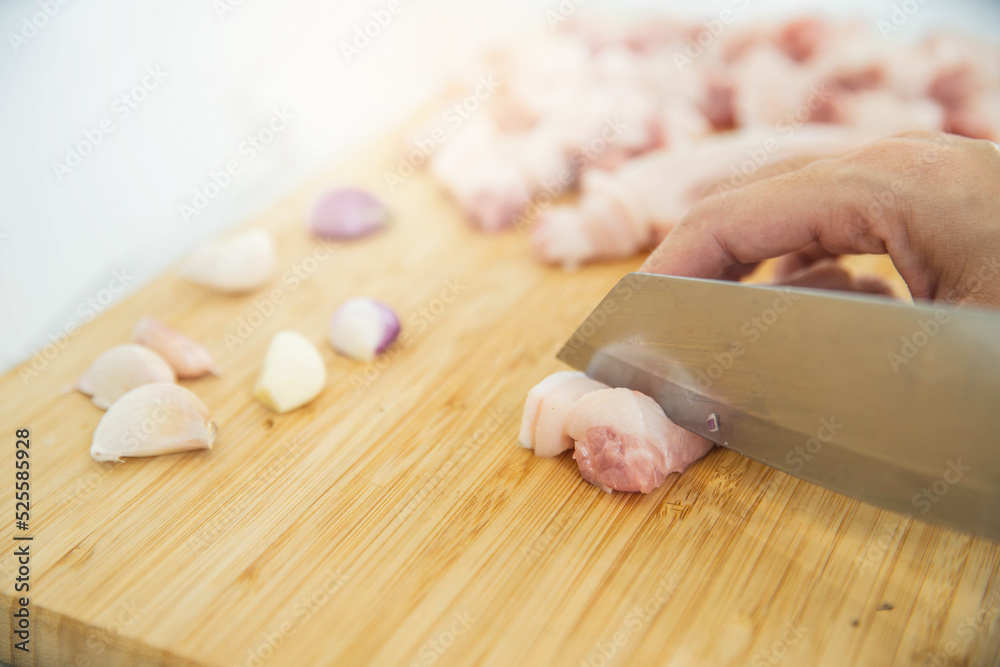 Woman cutting raw meat on wooden board in kitchen. Female hands with a knife in their hand cut fresh meat on a table.