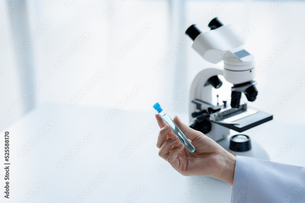 A laboratory assistant, a medical scientist, a chemistry researcher holds a test tube of chemicals and examines the disease from a patient's blood sample. Medicine and research concept. A laboratory assistant, a medical scientist, a chemistry researcher holds a test tube of chemicals and examines the disease from a patient's blood sample. Medicine and research concept.