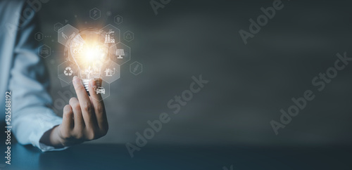 Person holding light bulb with earth hologram and renewable energy, hologram globe and wind energy used as pure renewable energy to reduce high cost oil, wind energy is natural energy. Global warming.